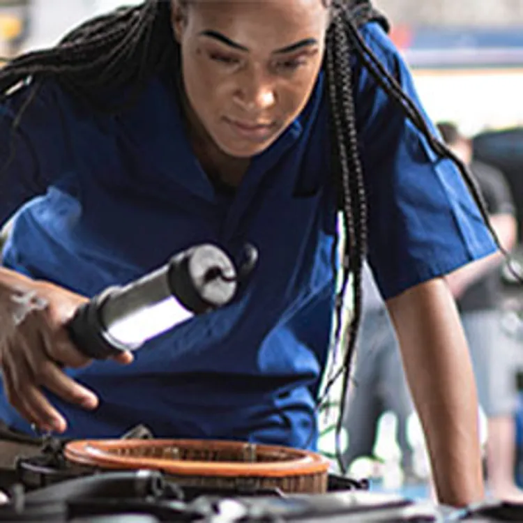woman mechanic looking under hood of car
