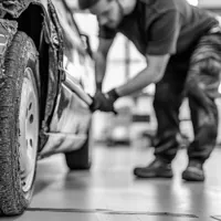man working on a damaged sedan