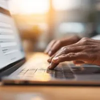 a close up of hands typing on a laptop keyboard