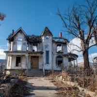 this is a two-story house that has been badly damaged by fire with the sky clear and blue, contrasting with the destruction