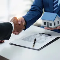 agent and client shake hands after signing papers