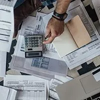 man looking over a lot of bills with calculator and computer
