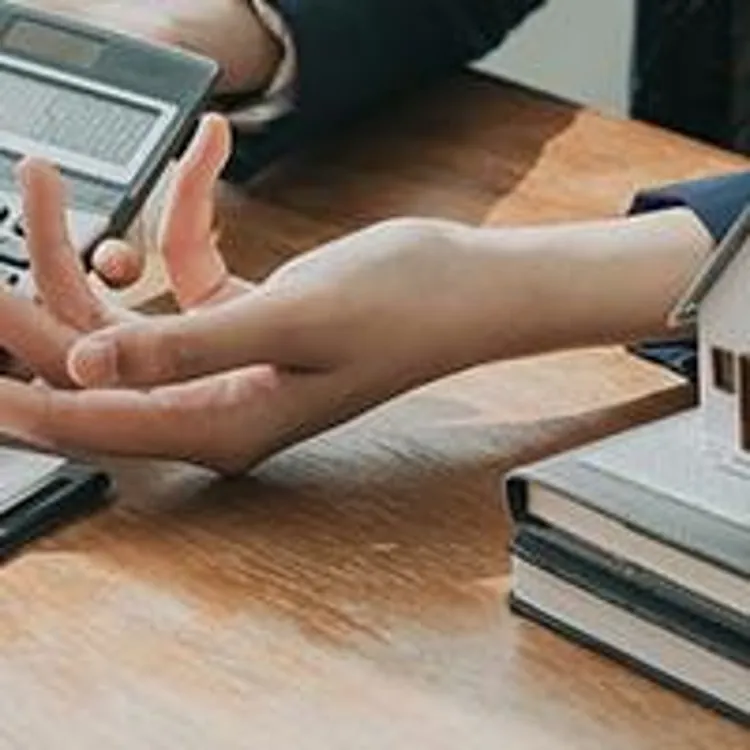 agent holding a calculator with miniature house