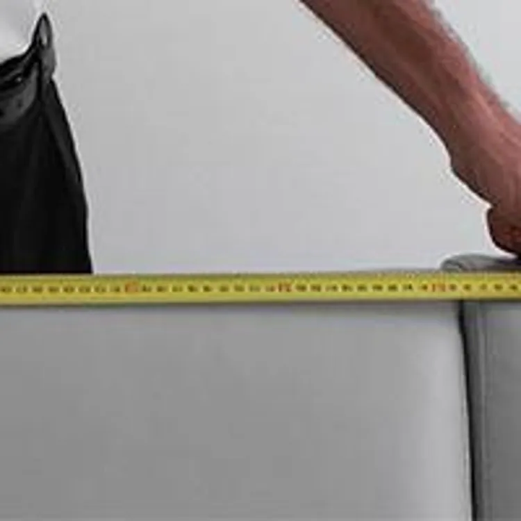 man measuring a couch with a measuring tape