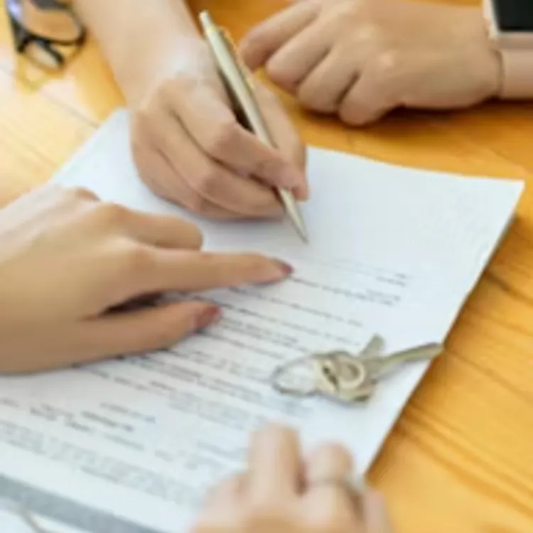 Hands signing home contract with keys and small house model on table
