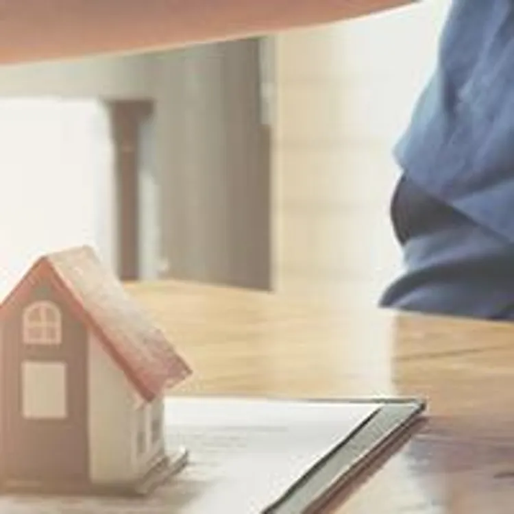 broker shaking purchasers hand behind model home and keys