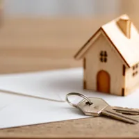 wood model house and keys on top of a letter envelope