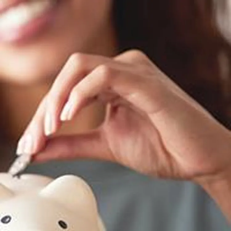 woman happily depositing a coin into a piggybank