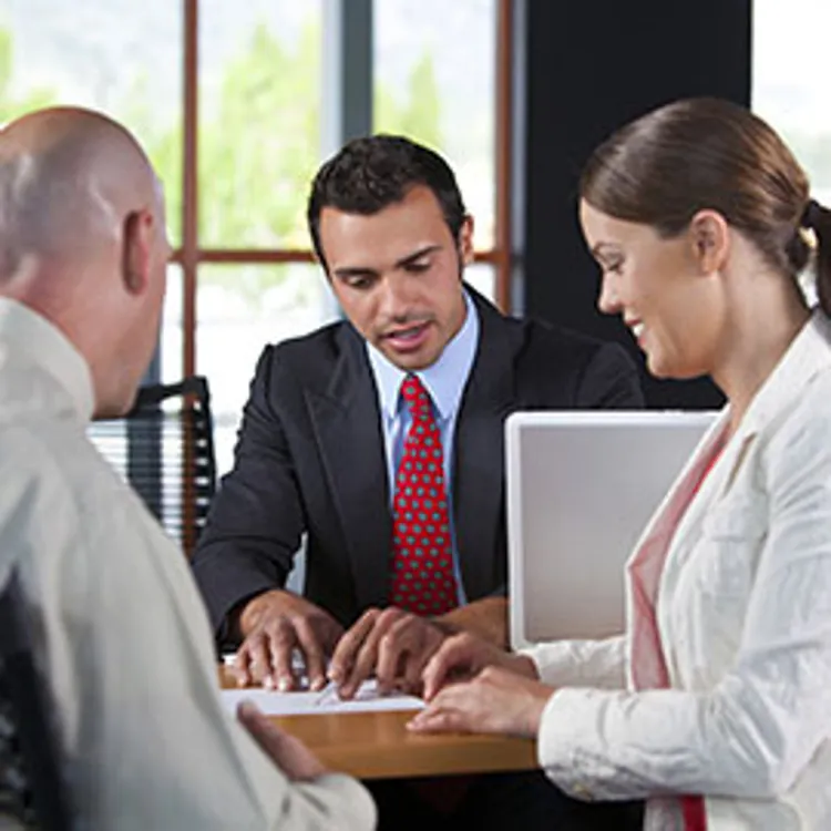 bank employee guiding a couple in signing loan documents