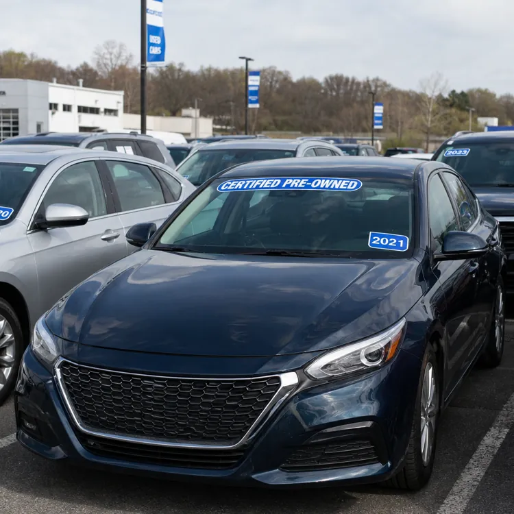 Row of certified pre-owned cars with year labels at a dealership lot