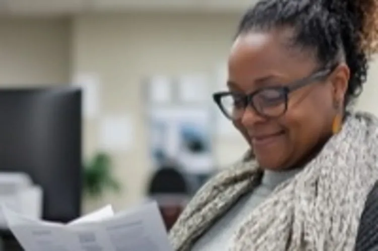a black woman smiling and reading a document