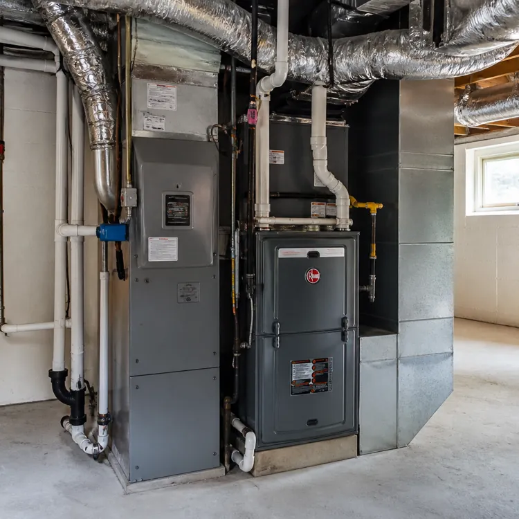 central furnace and ductwork in a clean unfinished basement with exposed pipes