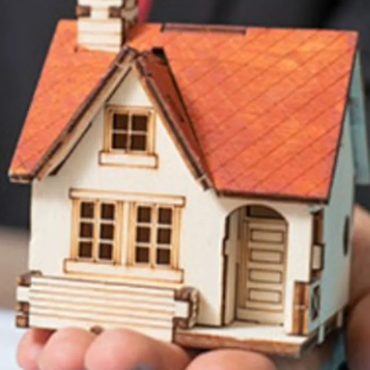 man holding a miniature house while signing a document