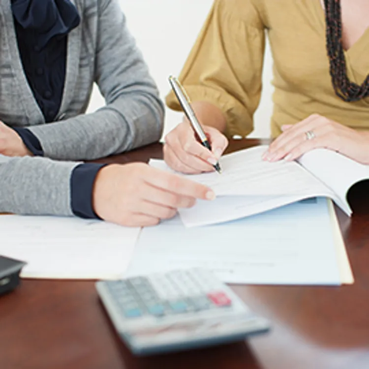 woman signing paperwork with agent looking over