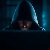 a man wearing a hood sitting in front of a computer