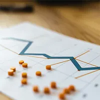 image showing a graph and red pins on a table