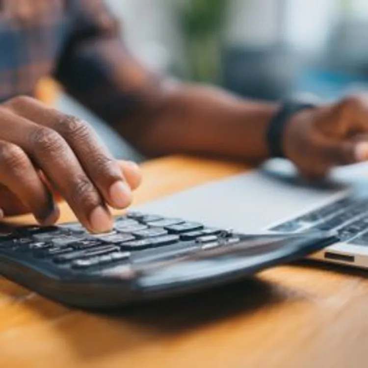 a person making calculations using his calculator and laptop
