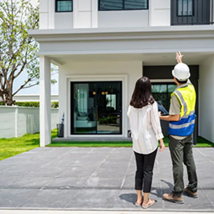Home inspector discusses issues with homeowners while standing in front of the house