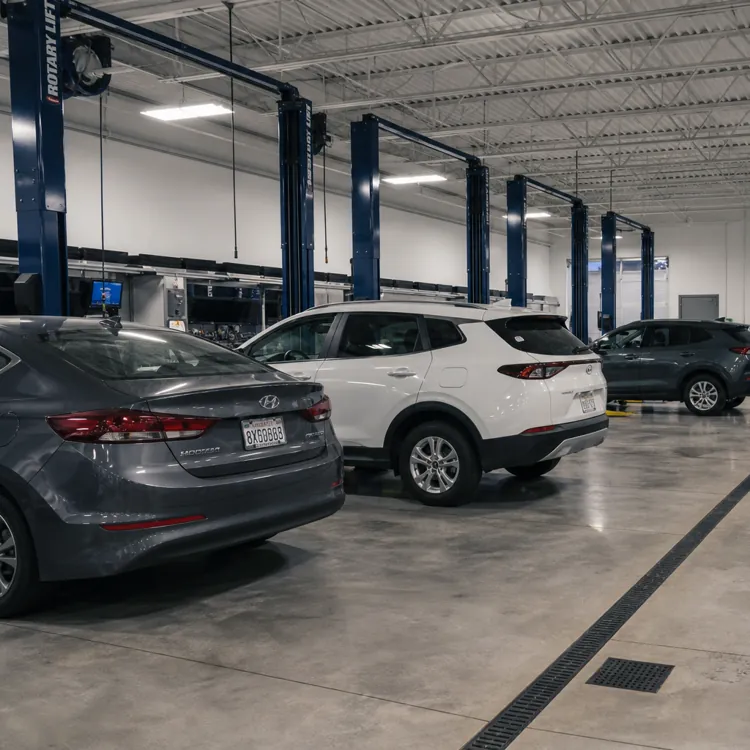 three cars parked inside a clean auto repair shop with workstations and lifts