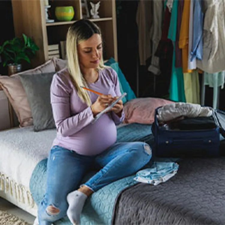 Pregnant woman packing hospital bag and writing a checklist