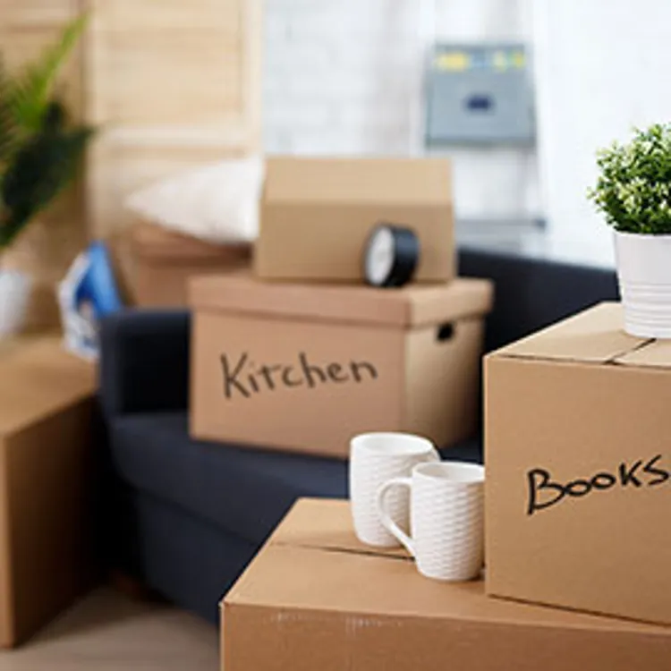 close up of labeled cardboard boxes with belongings stacked in new house