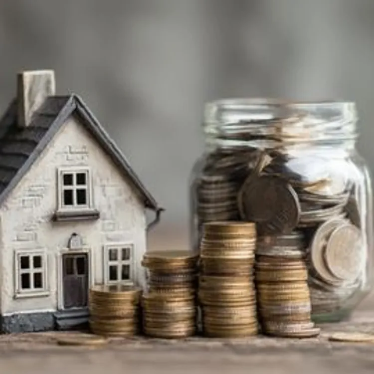 a toy house beside a jar of coins with four stacks of coins