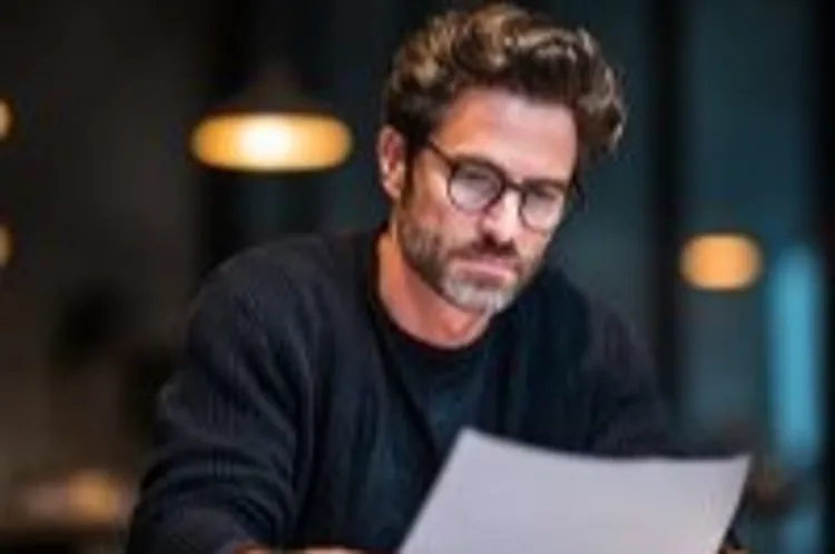 a man sitting while reading documents he is holding