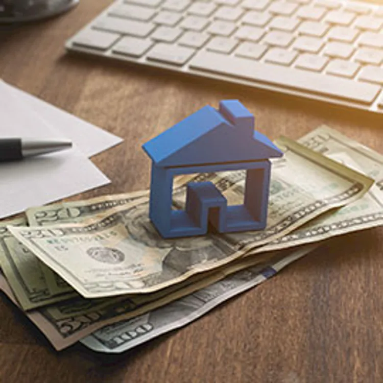 miniature house on top of dollar bills