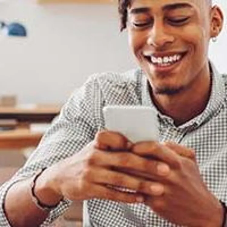 young man smiling while typing on phone