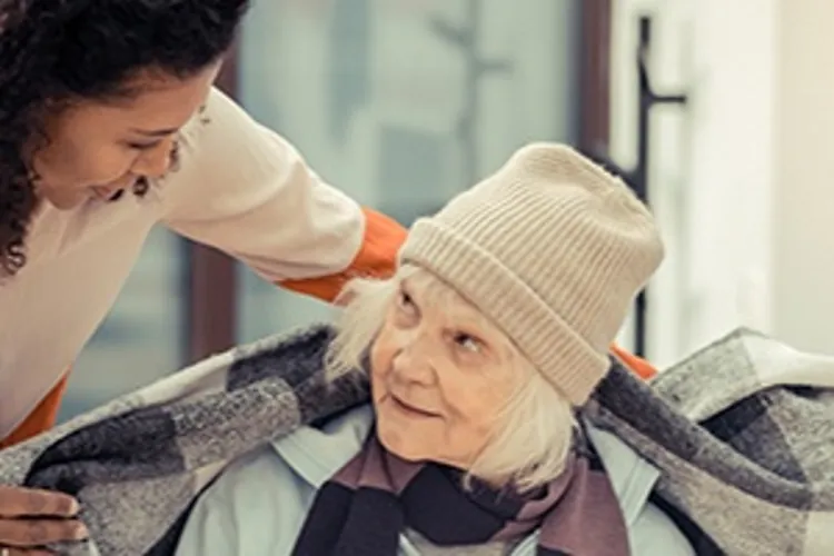 young woman wrapping homeless woman with blanket