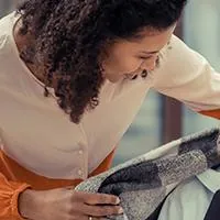 young woman wrapping homeless woman with blanket